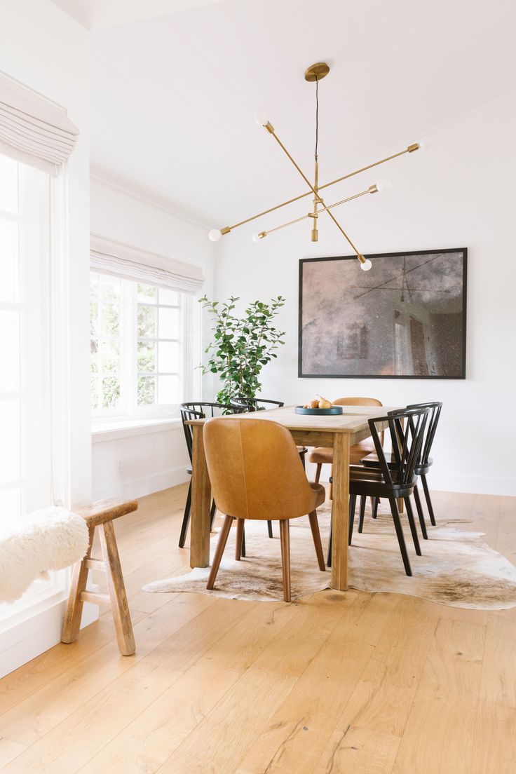 a dining room table with four chairs and a large painting on the wall above it