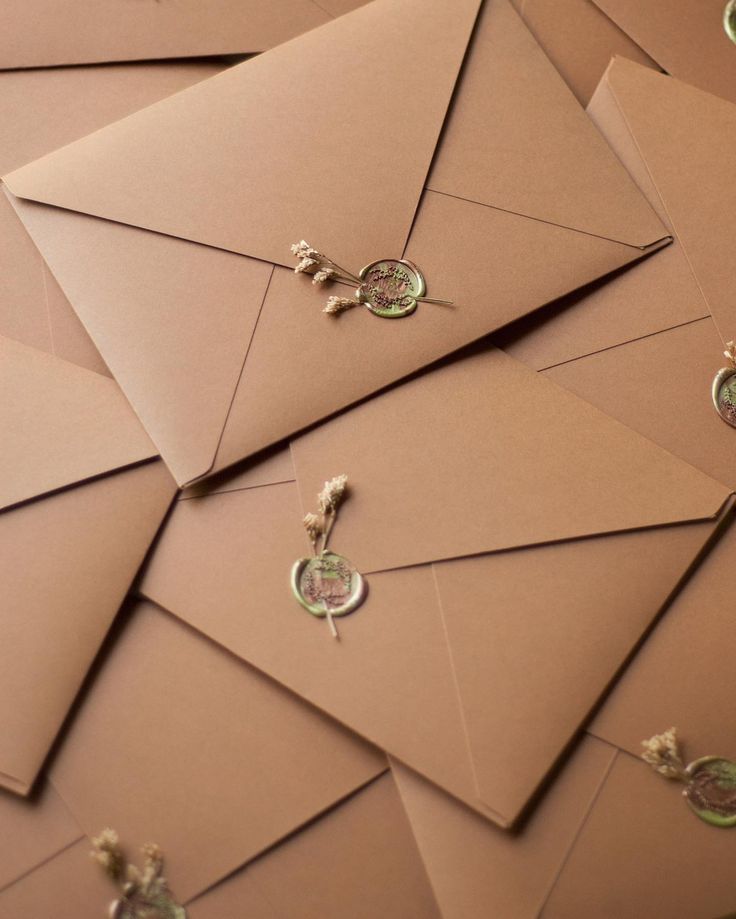 several envelopes are stacked on top of each other and have tiny charms attached to them