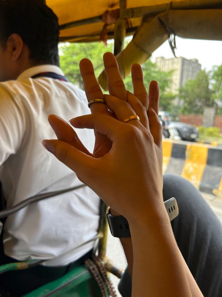 two people sitting in a vehicle with their hands up to the camera, and one person is holding his hand out