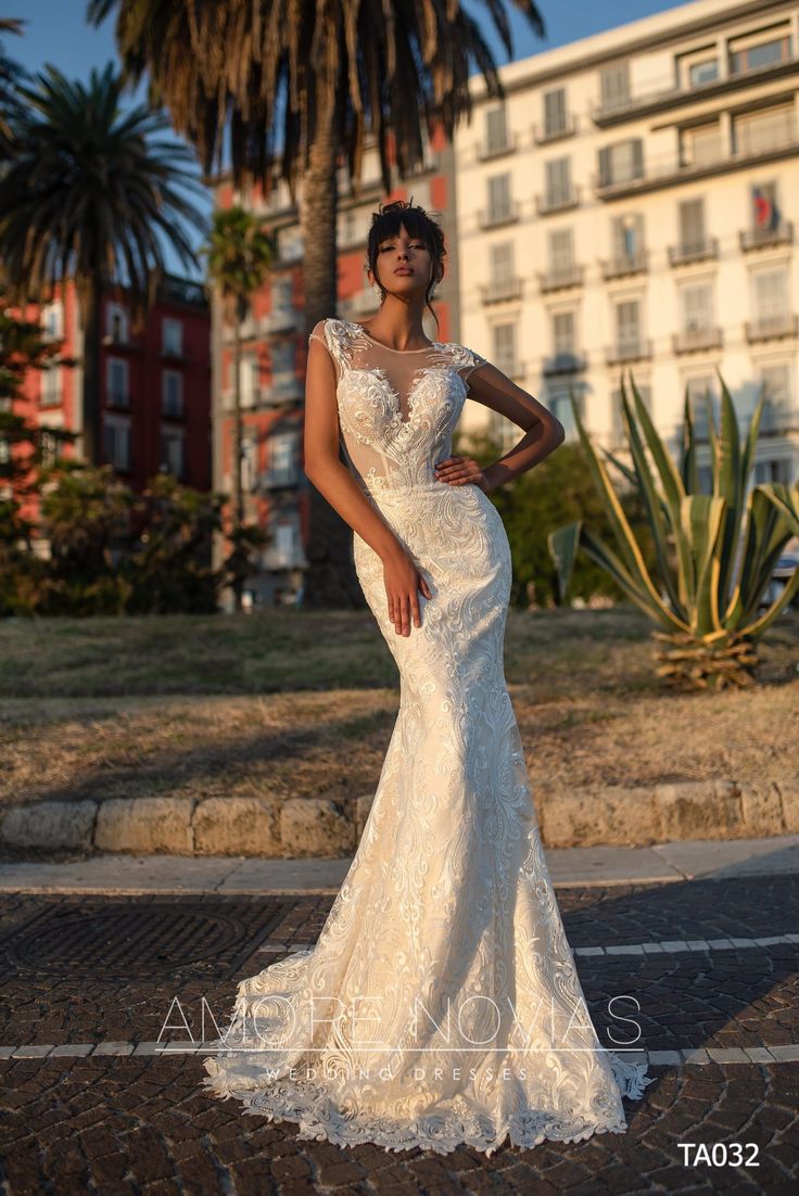 a woman in a white wedding dress standing on the street with her hands on her hips