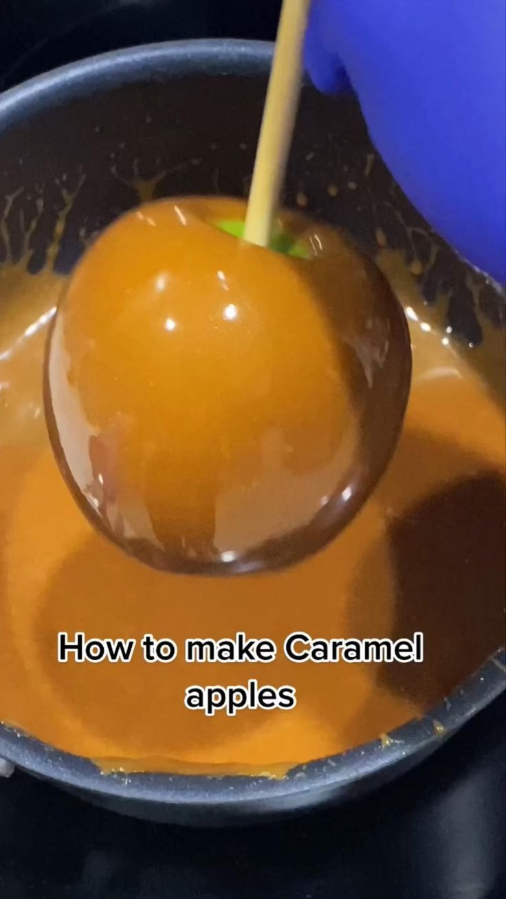 an apple being dipped into caramel sauce in a bowl with the words how to make caramel apples