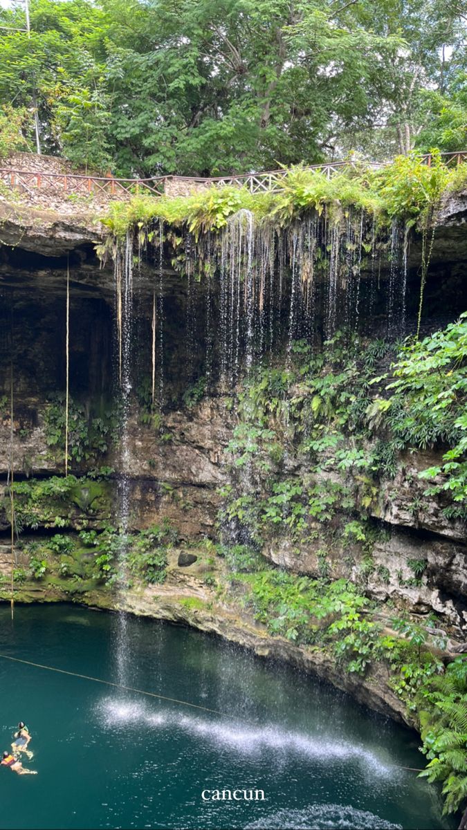 a person in a kayak near a waterfall with water falling off the cliff face