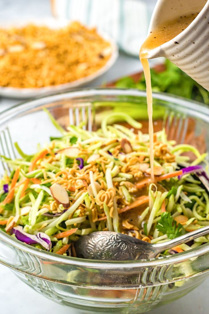 someone pouring dressing onto a salad in a bowl