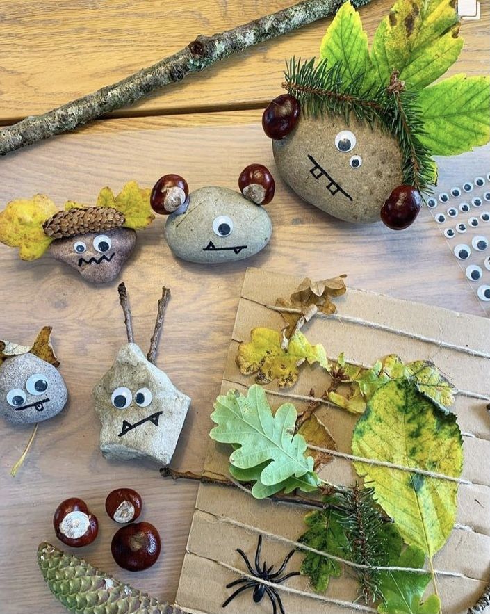 some rocks are sitting on a table with leaves and acorns in the shape of faces