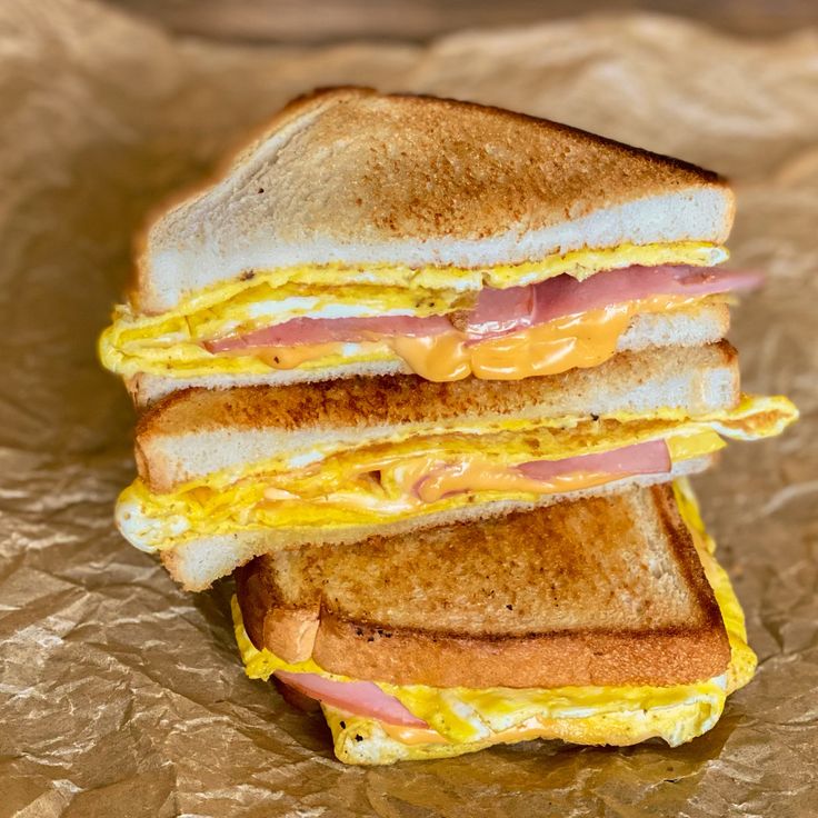 two sandwiches are stacked on top of each other with cheese and ham in between them