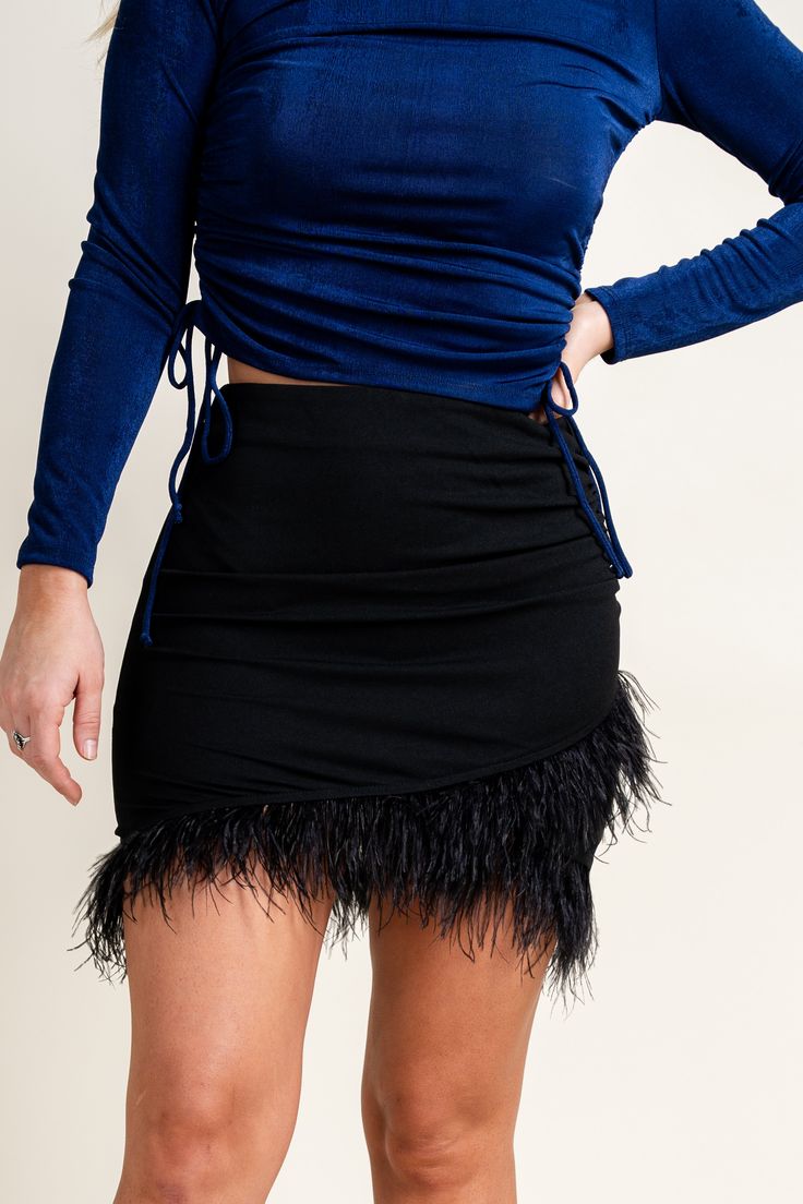 Feather trim wrap skirt from Lush Fashion Lounge women's boutique in Oklahoma City. Lush boutique in OKC has a variety of cute skirts! This trendy feather trim skirt is perfect for any New Year's Eve holiday party! Model is 5'6 size 26 wearing size small. 95% polyester 5% spandex Mini Wrap Skirt For Party, Party Mini Wrap Skirt With Lined Detail, Party Wrap Mini Skirt With Lining, Party Mini Wrap Skirt Lined, Chic Mini Skirt With Feather Trim For Party, Chic Party Mini Skirt With Feather Trim, Feather Trim Mini Skirt For Party, Black Mini Wrap Skirt For Party, Black Asymmetrical Wrap Skirt For Party