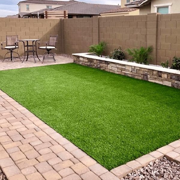 a backyard area with grass and brick pavers