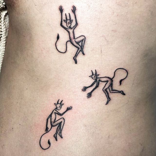 three small tattoo designs on the side of a woman's stomach, depicting two dancing cats