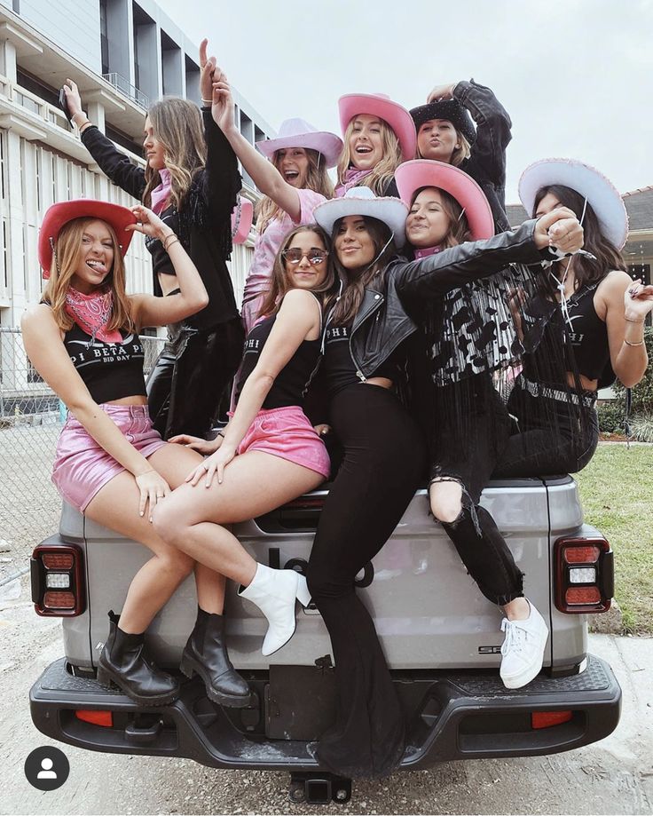 a group of women sitting on the back of a pick up truck posing for a photo