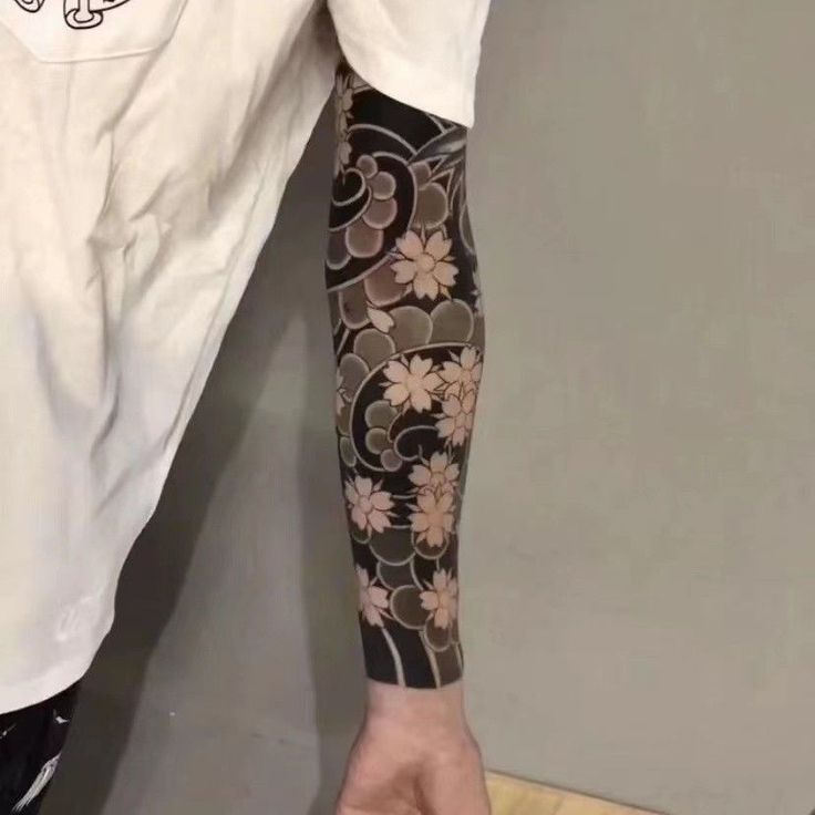 a man with a tattoo on his arm holding onto a piece of paper that has flowers on it