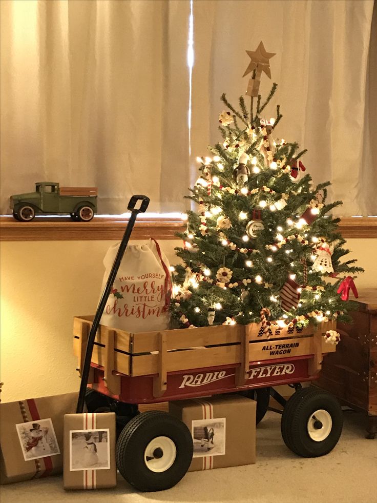 a small christmas tree in a wagon with presents under it and an old fashioned toy truck