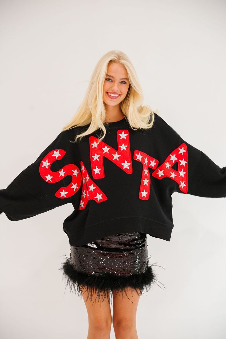 Spread holiday cheer with our HERE COMES SANTA Black Pullover! Featuring bold red Santa cutout letters and festive silver star patches, this cozy black pullover is perfect for the winter season. Be the life of the party and stay warm in style! All orders are currently shipping within 14 business days. To receive item quicker, expedited shipping is available at checkout. **All Christmas orders must be placed with expedited shipping to guarantee delivery by Dec. 24 if placed after Dec. 10. All 2-D Black Top For Holiday In Fall, Black Holiday Tops For Fall, Black Tops For Holiday In Fall, Black Tops For Seasonal Wear, Black Tops For Fall Holiday, Black Sweater For Holiday In Fall, Black Long Sleeve Sweatshirt For Holiday, Casual Winter Party Sweatshirt, Winter Party Sweatshirt With Crew Neck