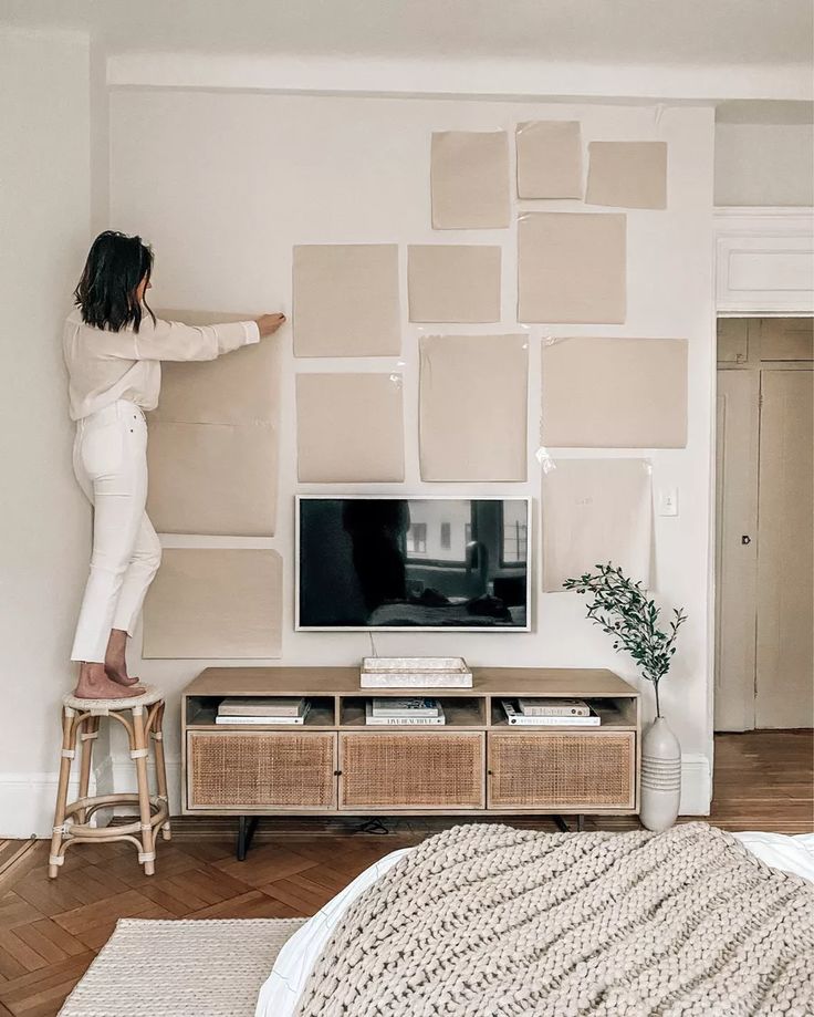 a woman standing on a stool in front of a tv with paint swatches all over it