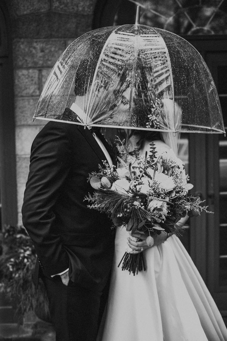 a bride and groom under an umbrella on their wedding day in black and white photo