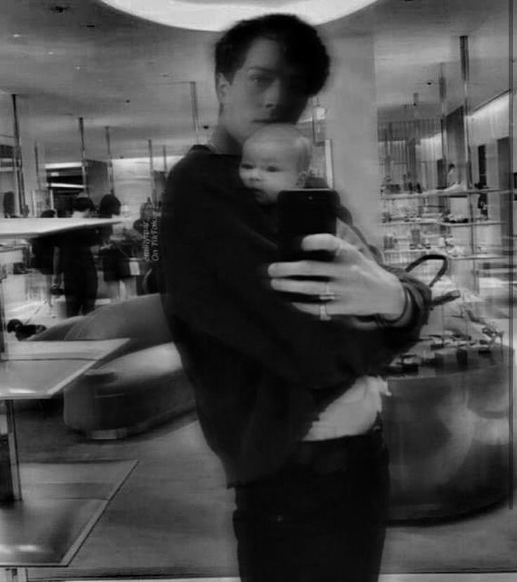 a man holding a baby in his arms while standing next to an airport checkout counter