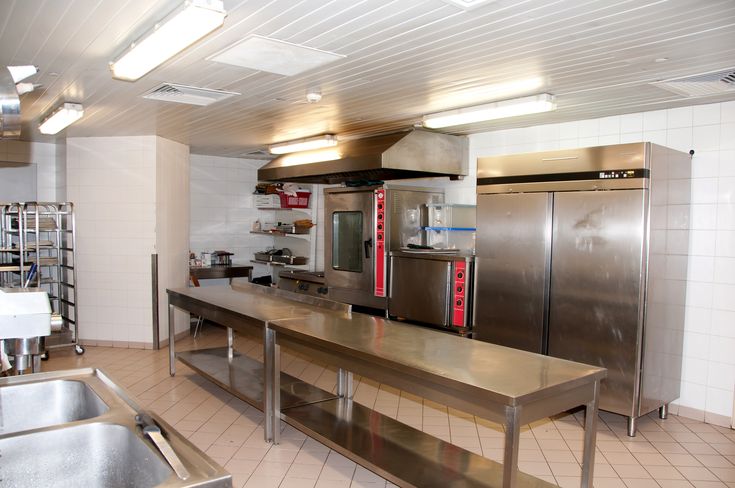 a commercial kitchen with stainless steel appliances and counters in the center, along with tiled flooring