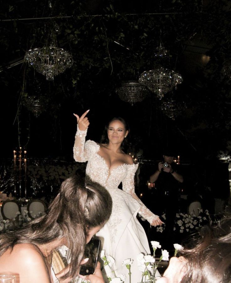 a woman in a white dress standing on top of a table next to other people