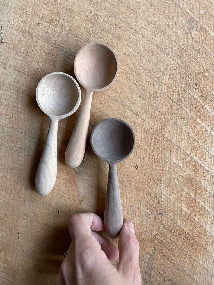 three wooden spoons on a table being held by a hand