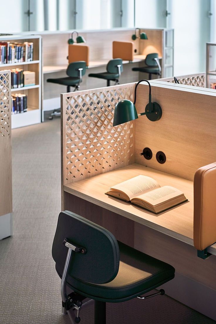 an open book is sitting on a desk with a chair in the foreground and several bookshelves behind it