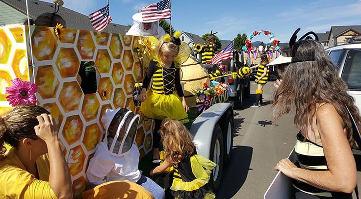 some people are standing in the back of a truck with bees on it and flags