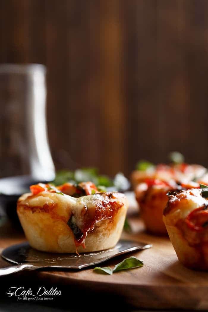 mini pizzas sitting on top of a wooden cutting board