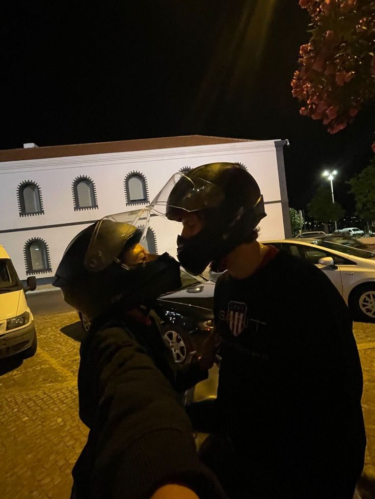 two people wearing helmets are standing in front of a building