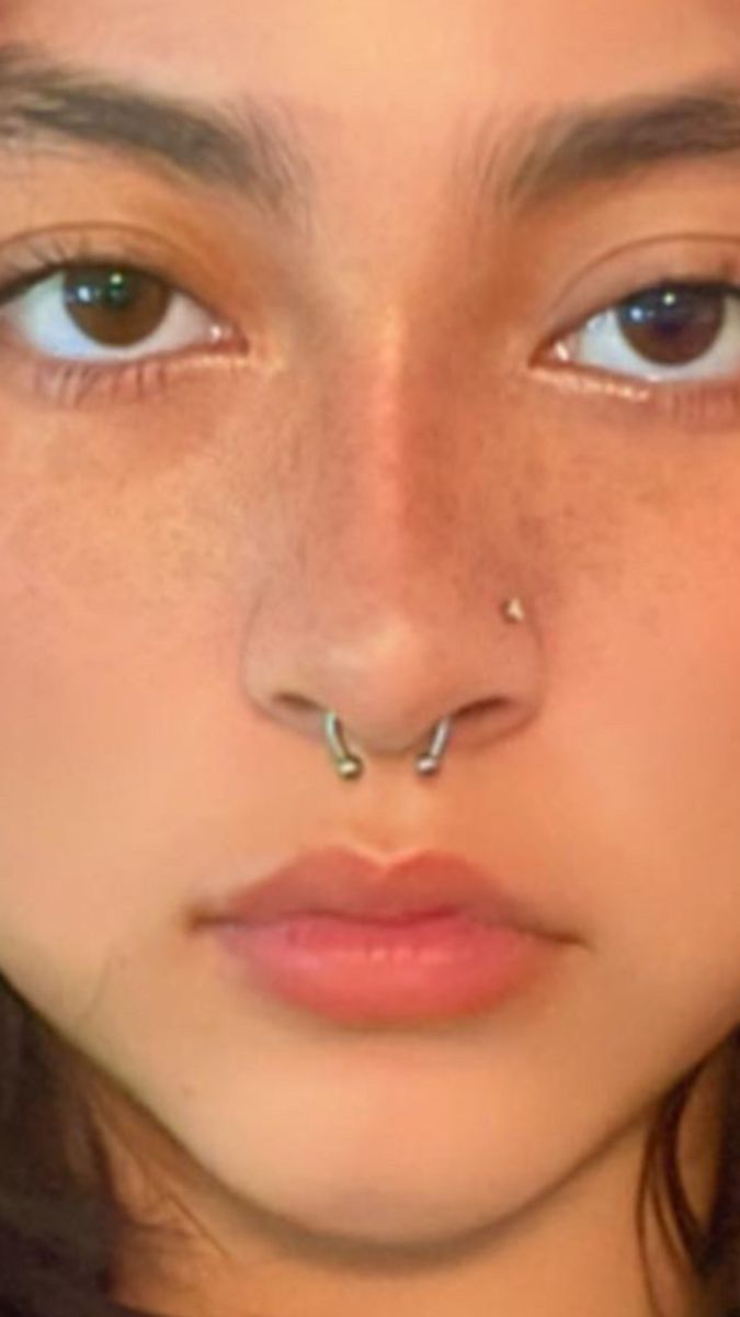 a woman with piercings on her nose and nose ring in front of her face