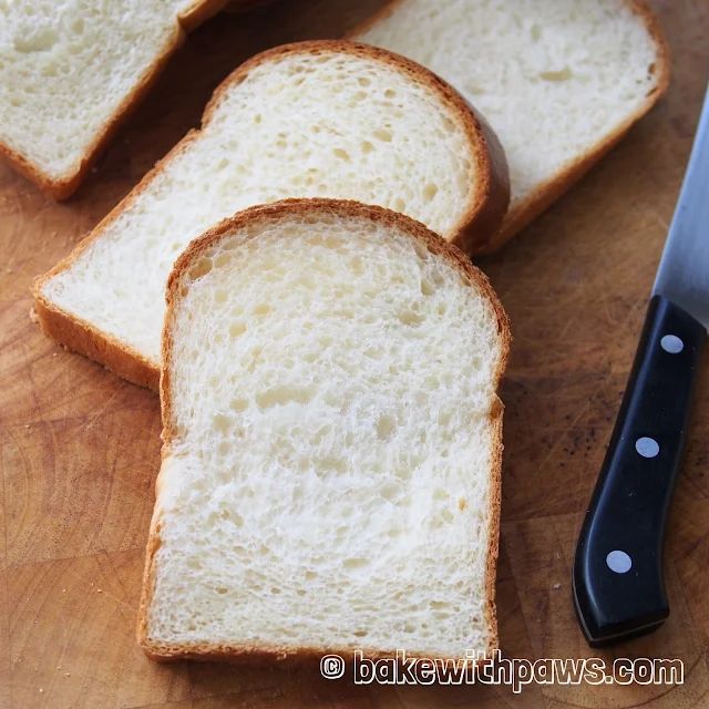 slices of white bread sitting on top of a wooden cutting board