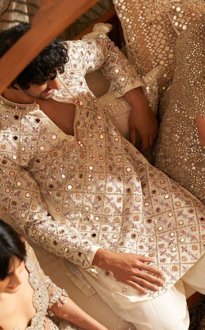 two women in gold and white outfits sitting on a bed