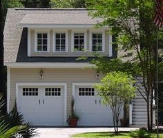 a white house with two garages and trees