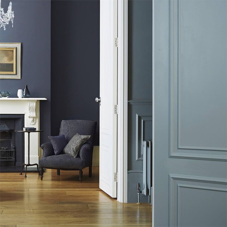 a living room with blue walls and white trim on the fireplace mantel, black chair, and chandelier