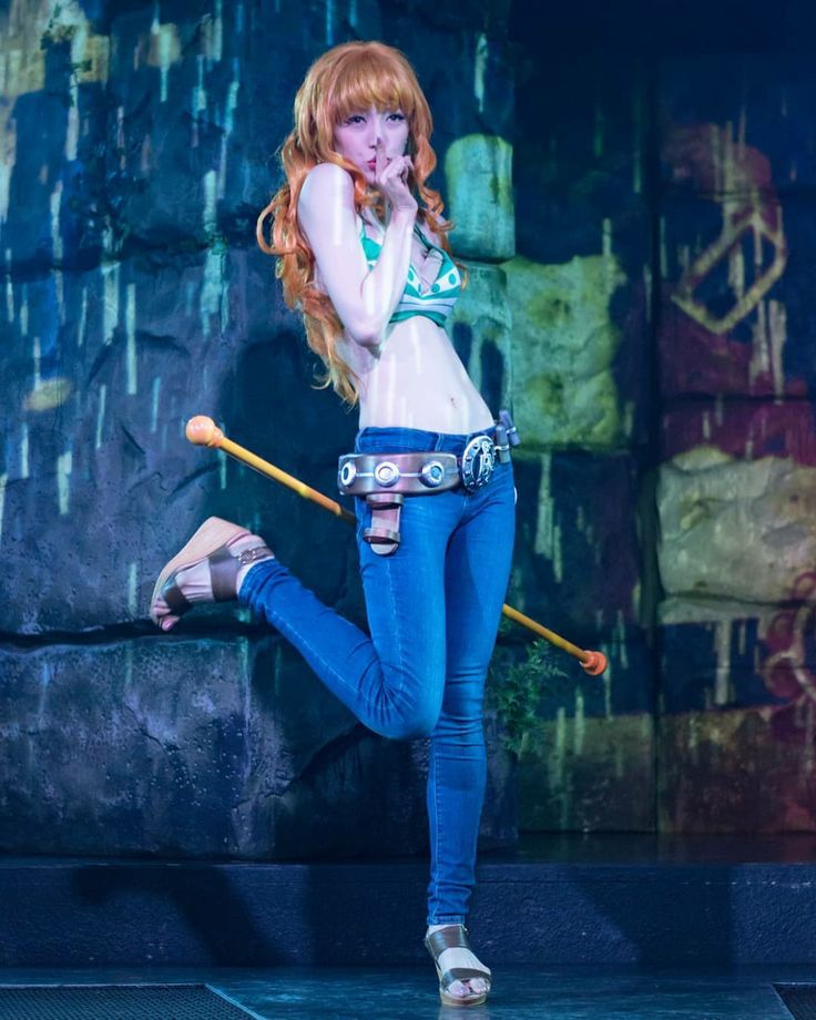 a woman with long red hair and blue jeans is holding a baseball bat in her right hand