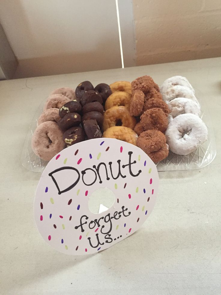 donuts are sitting in a plastic container on a counter top with a sign that says, donut forget us