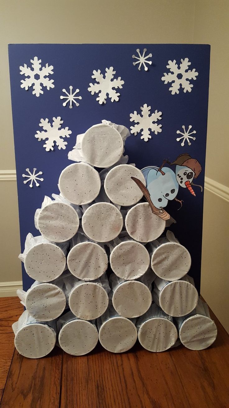 a christmas tree made out of paper plates on top of a wooden floor with snowflakes in the background