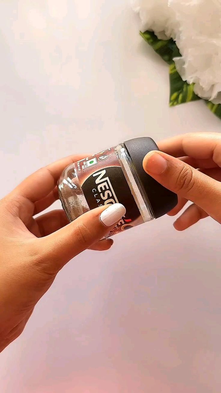 a woman holding onto a cell phone with her hand on the back of it and white flowers in the background