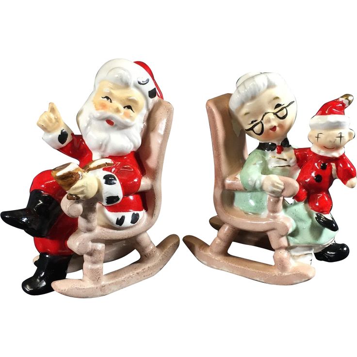 two figurines of santa and mrs claus sitting on rocking chairs, one holding a baby