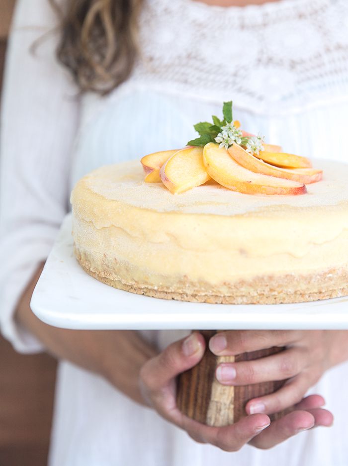 a woman holding a cake with peaches on top