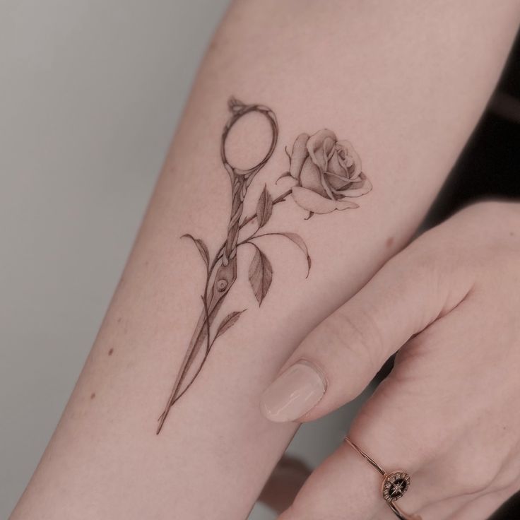 a woman's arm with a rose tattoo on the left side of her arm