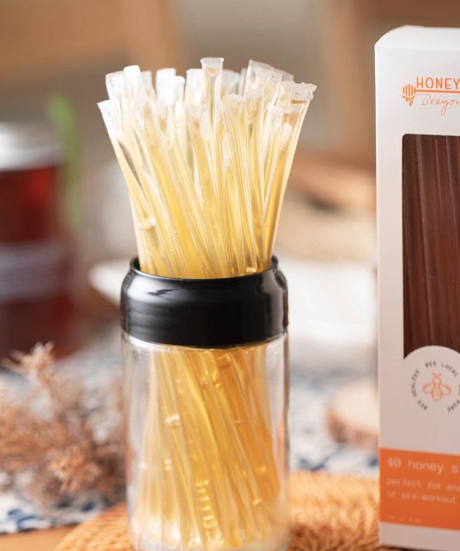 a glass jar filled with yellow pasta noodles next to a box of honeywax