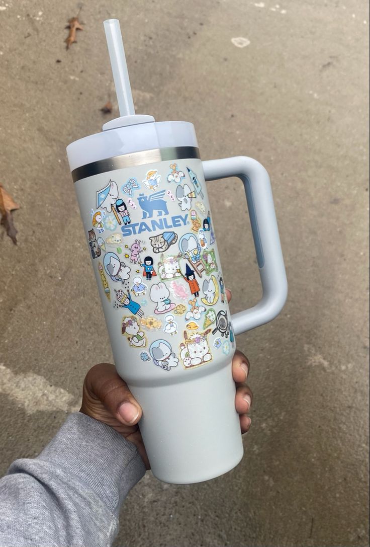 someone is holding up a cup with stickers on it and the lid has a straw in it