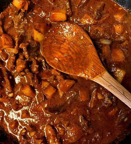 a wooden spoon in a pot filled with stew