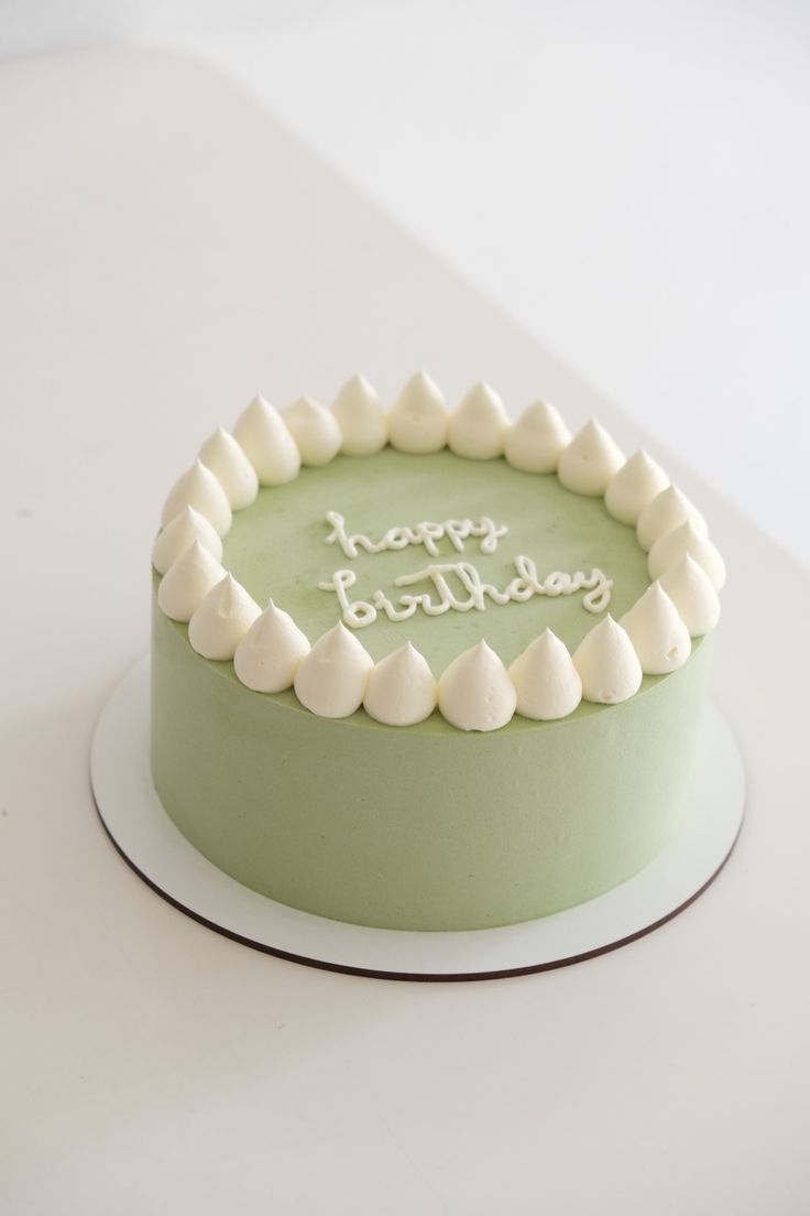 a green birthday cake with white frosting that says happy birthday on it's top