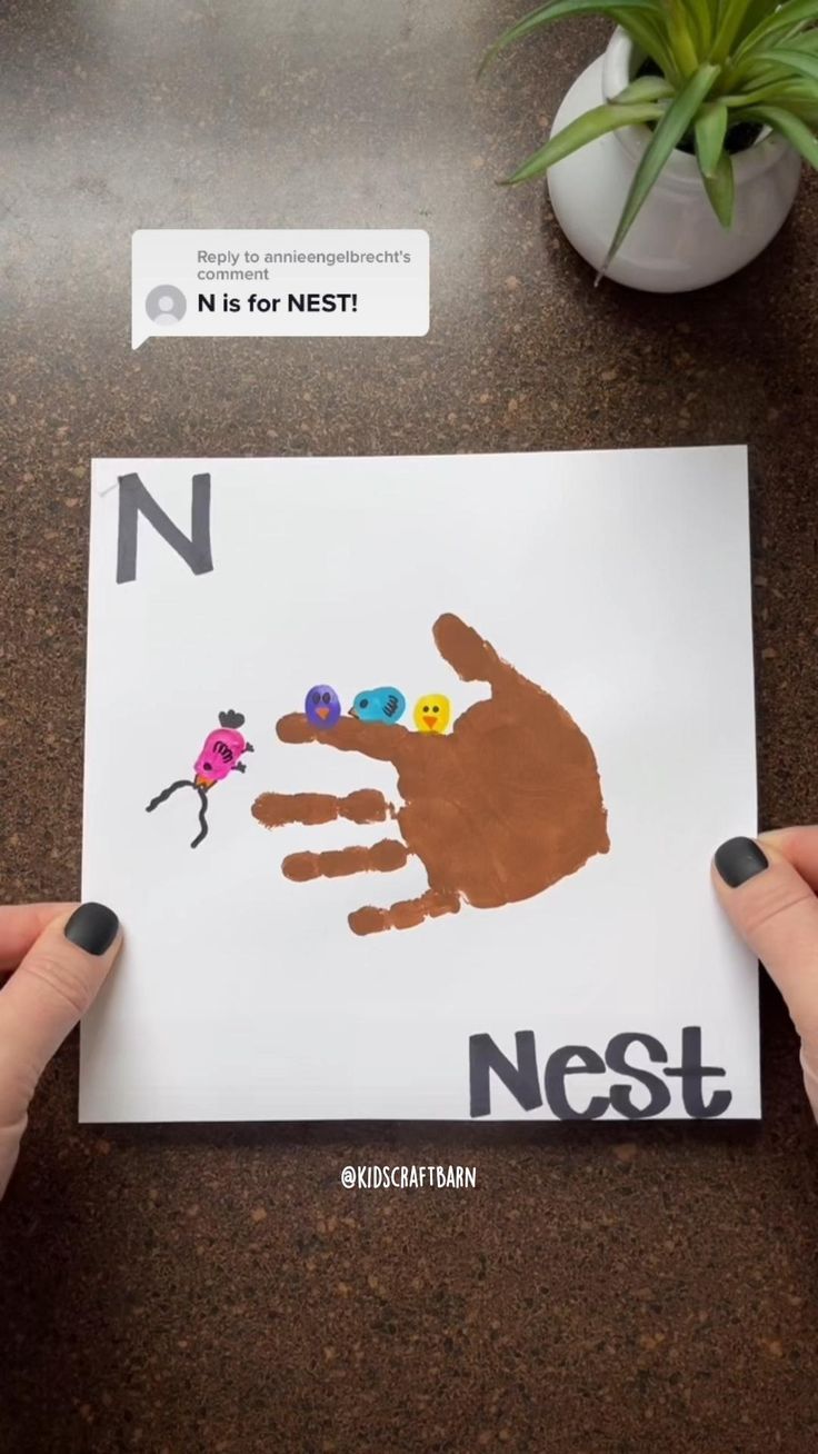 two hands holding up a handprint with the letter n in front of it and a plant