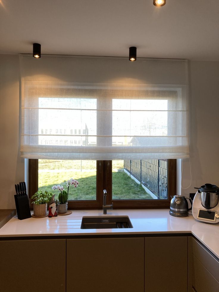 a kitchen with an open window, sink and coffee pot on top of the counter