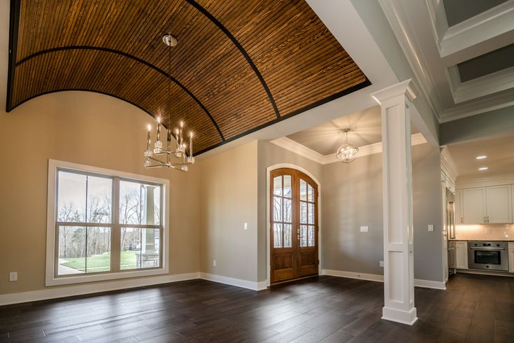 an empty living room with wood floors and a chandelier hanging from the ceiling