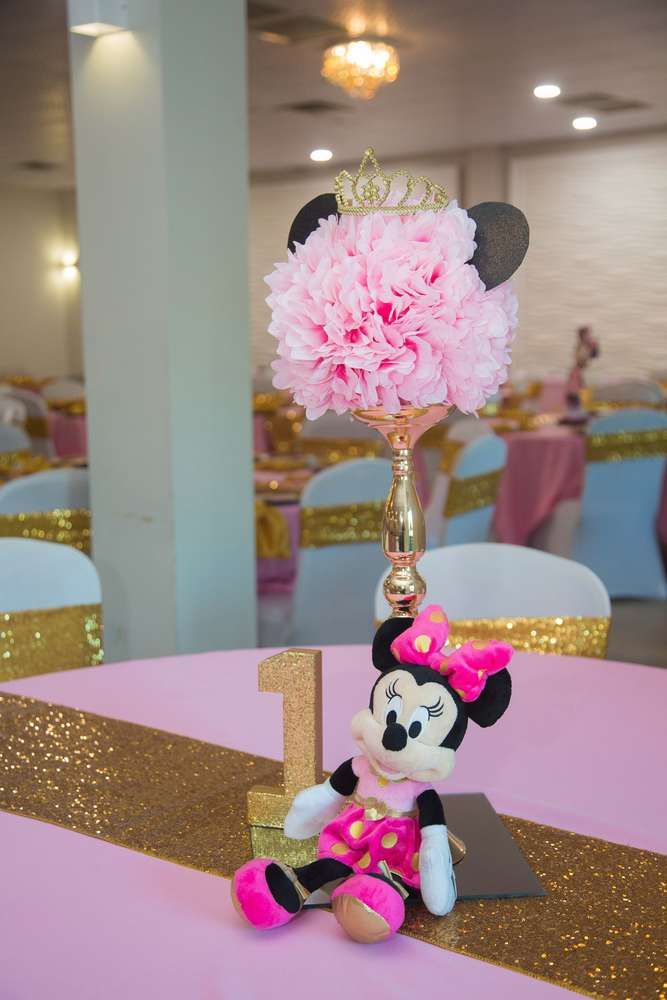 a minnie mouse centerpiece on top of a table at a birthday party with pink and gold decorations