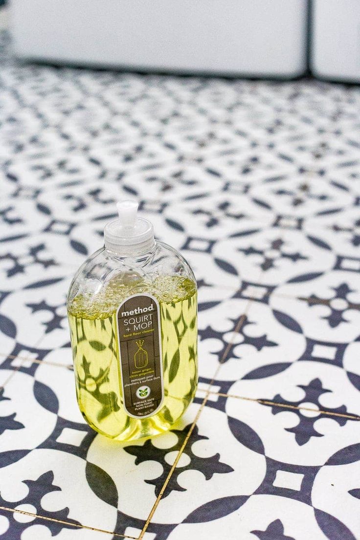 a bottle of liquid sitting on top of a tiled floor