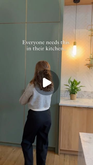 a woman standing in front of a green wall with the words everyone needs this in their kitchen