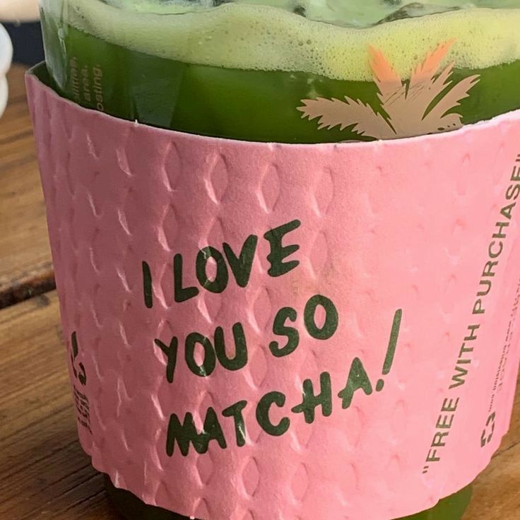 a pink cup filled with green liquid sitting on top of a wooden table