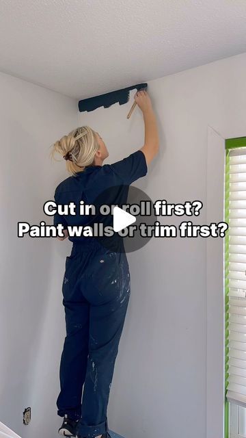 a woman is painting the wall with paint rollers